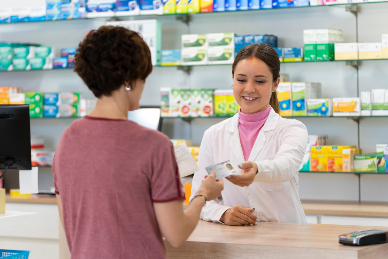 Frau gibt einer Apothekerin ihre Gesundheitskarte.