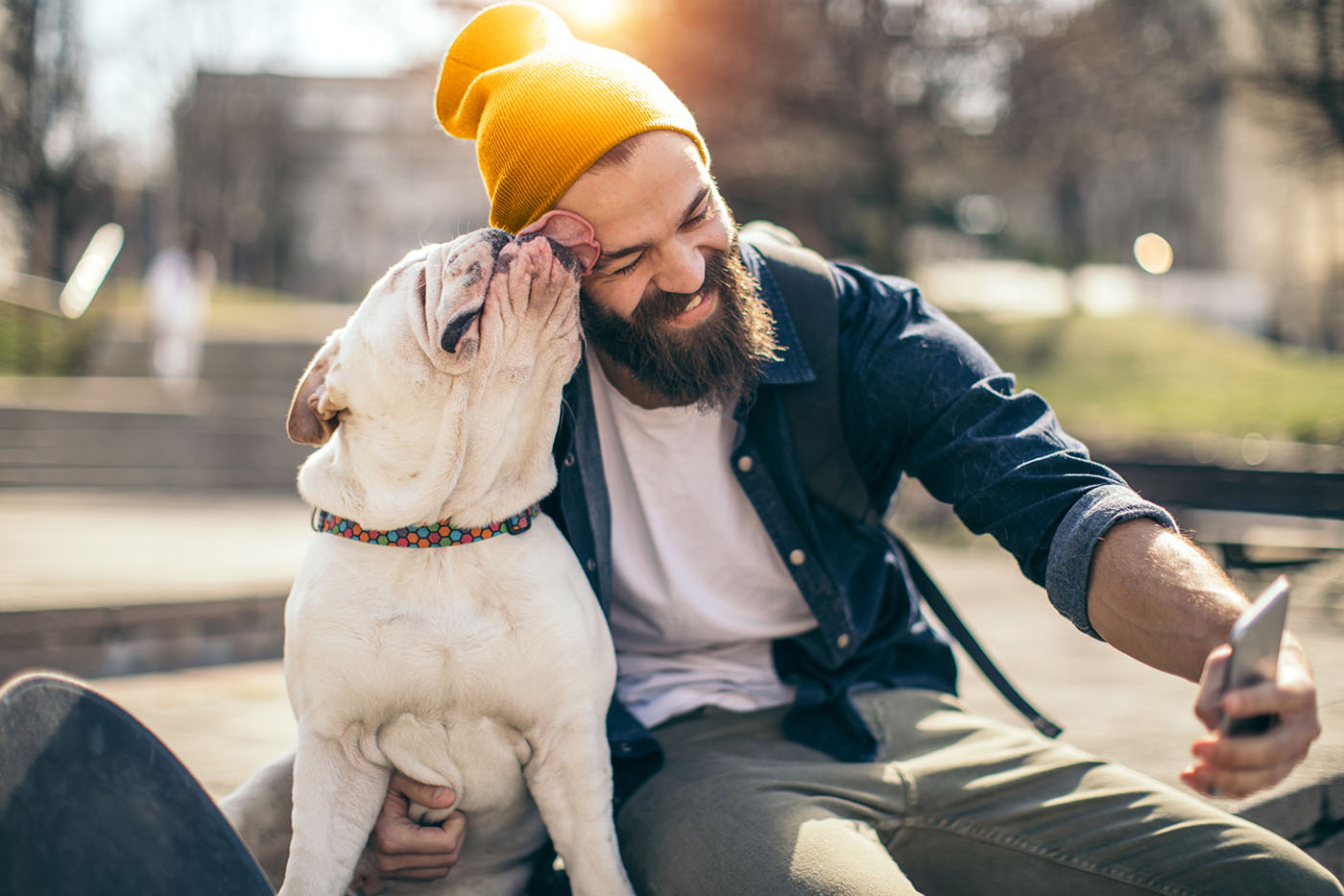 Mann, der sich über den Gesundheitsbonus freut und der von seinem Hund im Gesicht abgeleckt wird