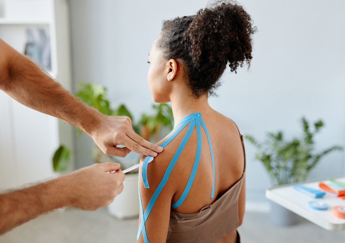 Frau erhält an der Schulter kinesiologisches Taping.