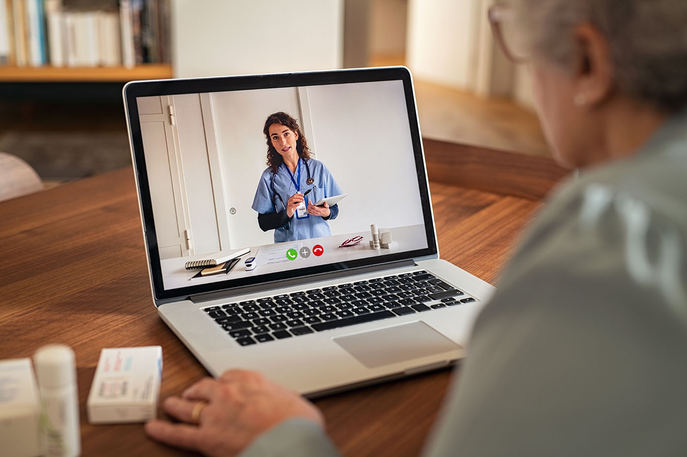 Seniorin, die vor einem Laptop sitzt und virtuell mit einer Ärztin spricht