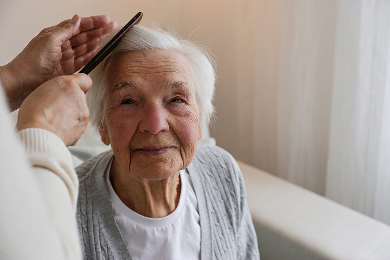 Einer Seniorin werden die Haare gekämmt