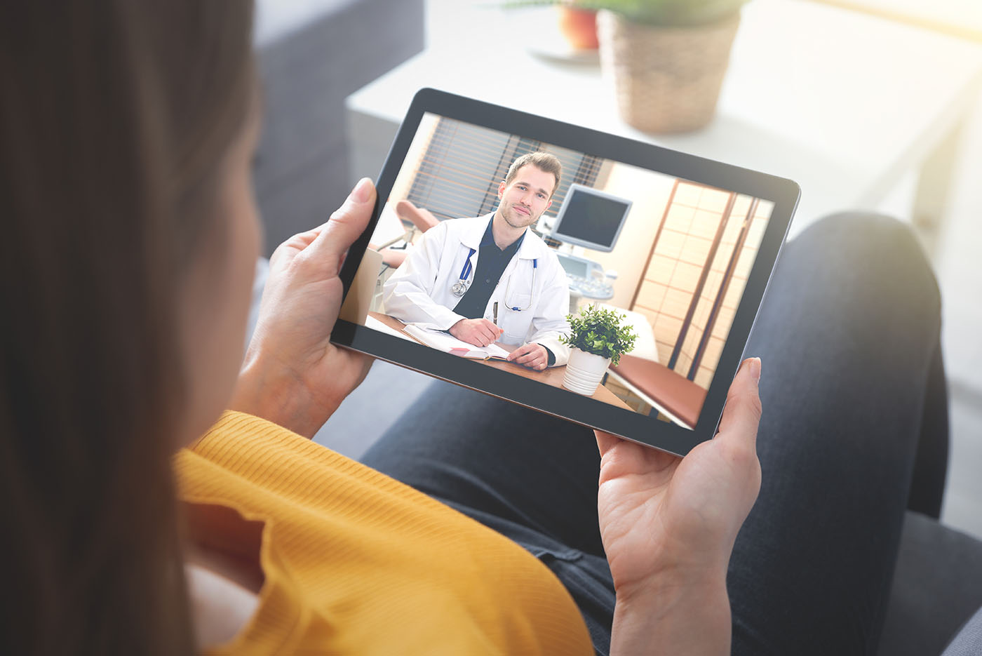 Frau zu Hause, die auf einem Tablet die Videosprechstunde von InfoMedicus nutzt