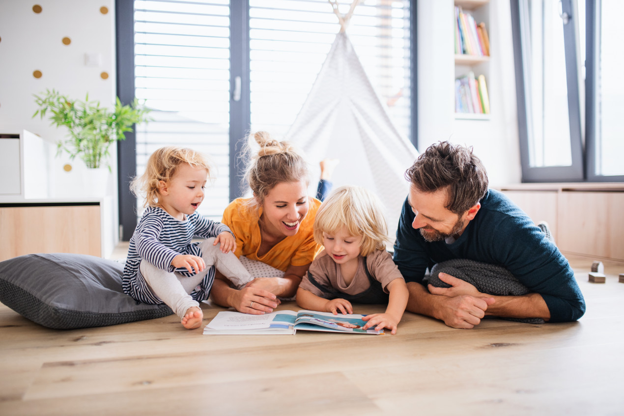 Familie, die gemeinsam auf dem Boden liegt und ein Buch anschaut